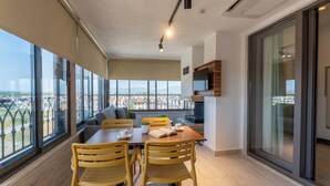 A modern dining area with a large table, yellow chairs, and a view of the cityscape through large windows. - ARVIA SUITES (Altinova)