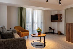 A modern living room with a sofa, armchair, and a small table with a plant.