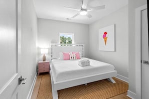A bedroom with a white bed, a nightstand, a ceiling fan, a window, and a wall-mounted artwork. - Boardwalk Bliss 2.5 Blocks to Ocean Pet Friendly (Myrtle Beach)
