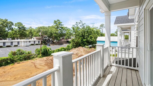 A covered porch with a view of a parking lot and a building with a blue exterior. - Swell House-2.5 Blocks to Ocean-Pet Friendly (Myrtle Beach)
