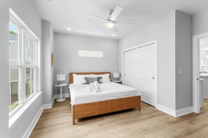 Ein Schlafzimmer mit einem großen Bett, einem Deckenventilator und Blick ins Freie.