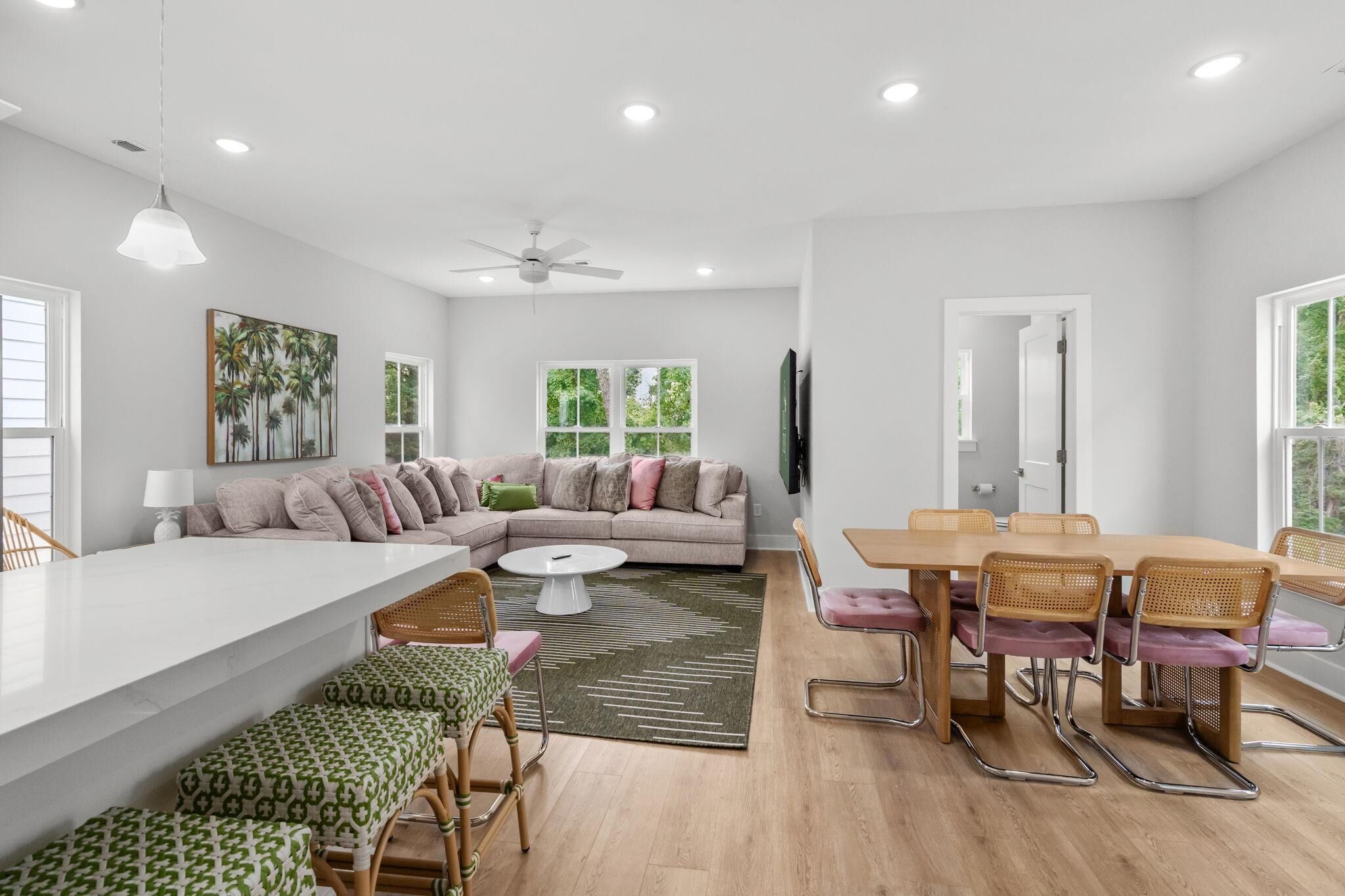A modern living space with a sofa, dining table, chairs, and a ceiling fan.