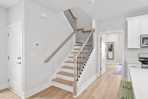 Een modern interieur met een houten trap, witte muren en een keukenhoek.