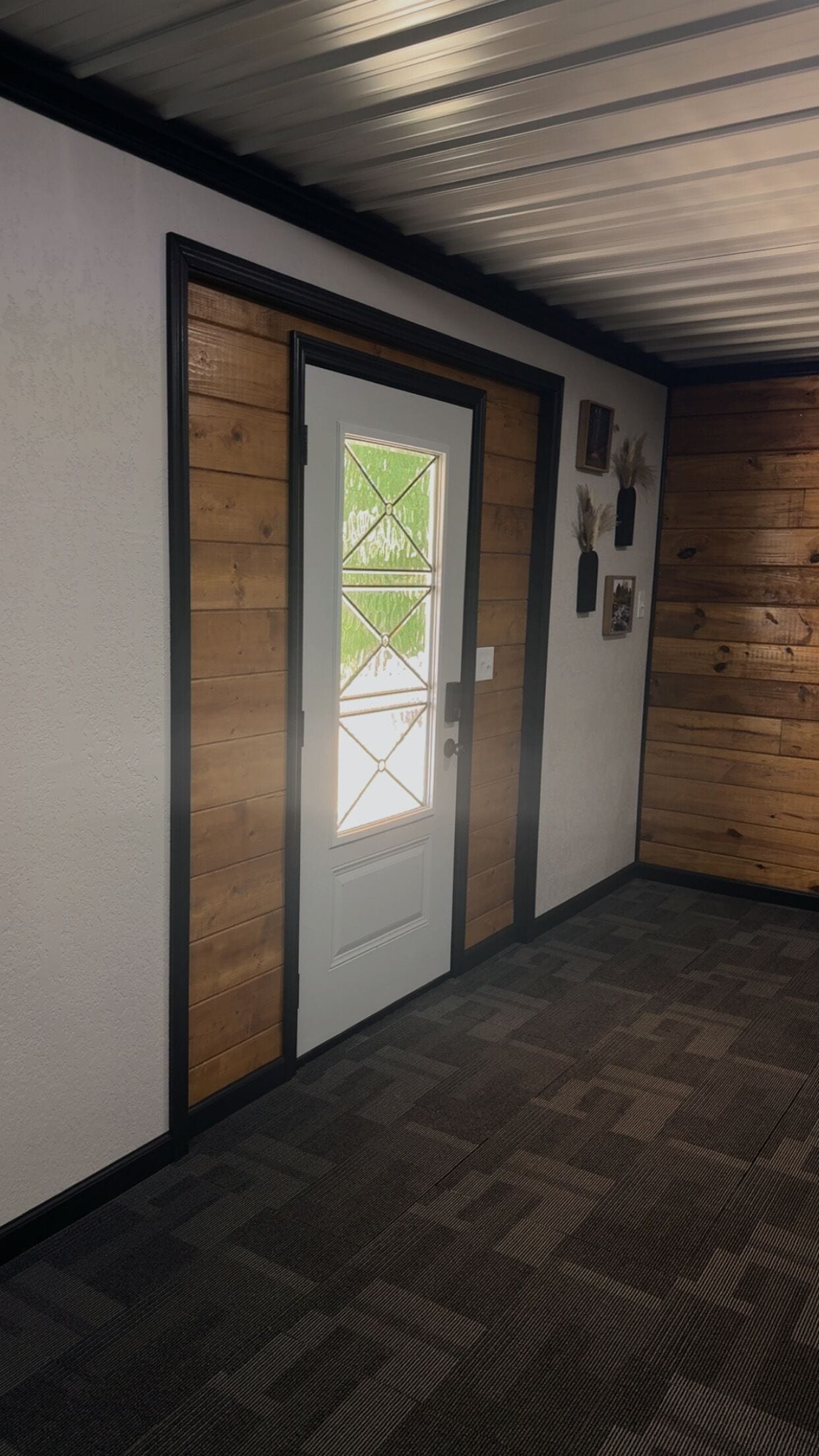 A hallway with a wooden door and a patterned carpet.