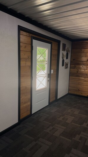 A hallway with a wooden door and a patterned carpet.