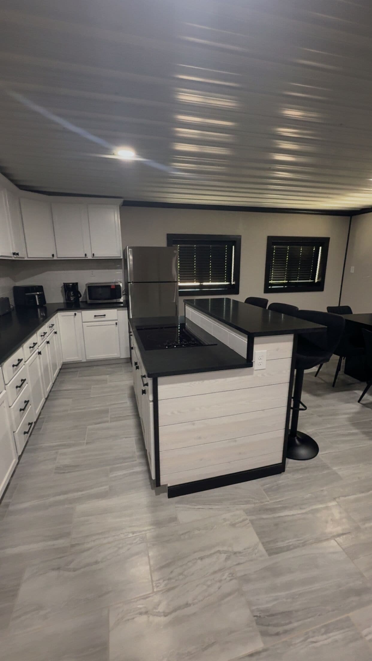 A modern kitchen with white cabinets, a black countertop, and a built-in stove.