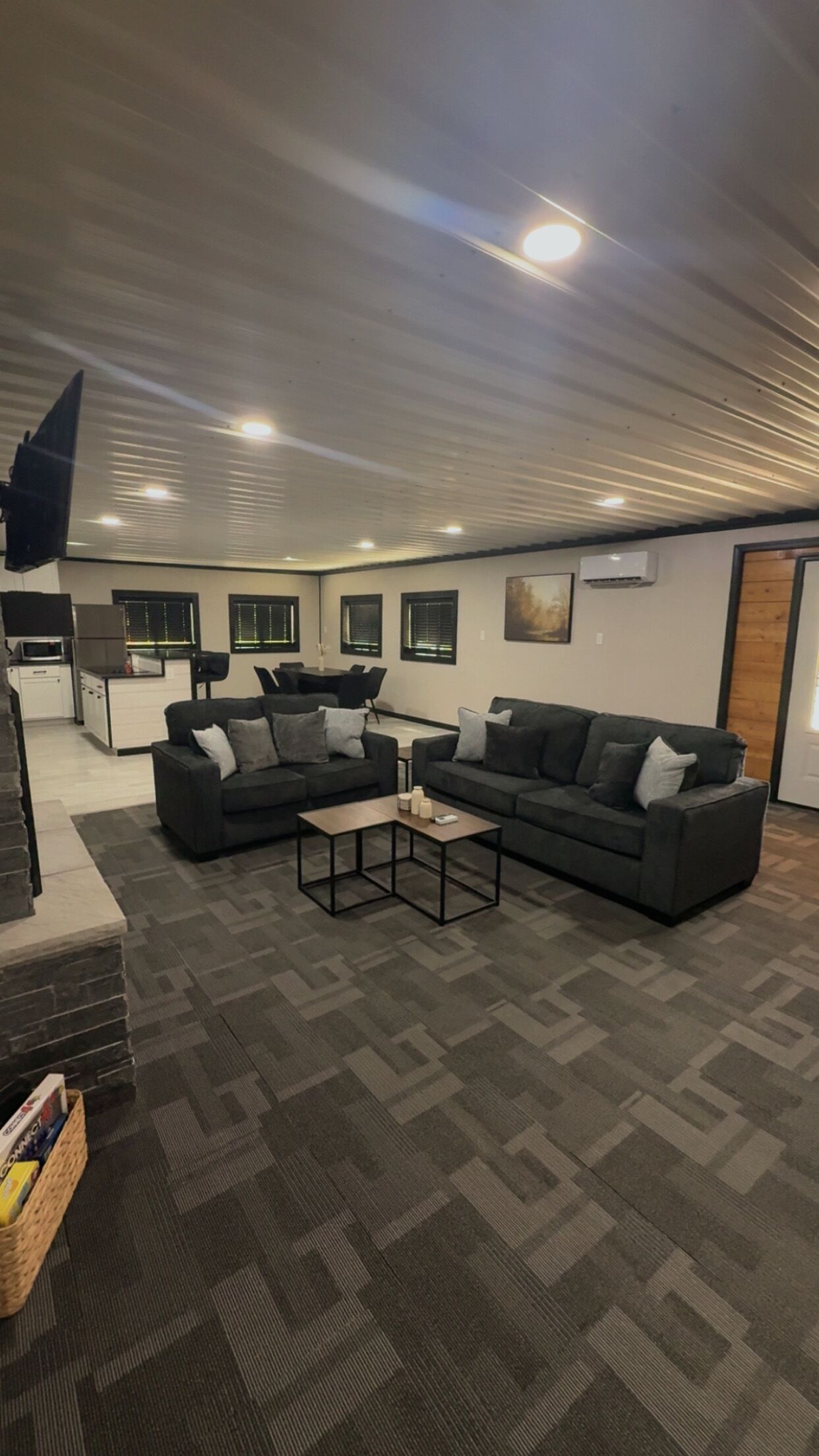 A modern living room with a sectional sofa, a coffee table, and a kitchen area in the background.