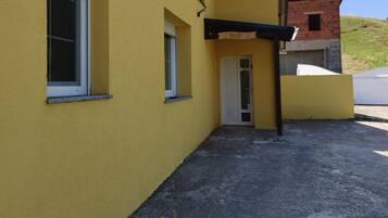 A yellow building with a small door and windows, a gravel driveway, and a clear blue sky.