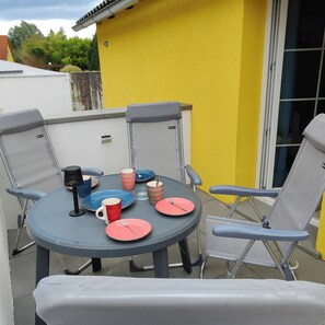 An outdoor dining area with a table and four chairs, a yellow wall, and a window. - Einsiedler Vacation Rental - Sleeps 4, with a terrace and grill, dog-friendly (Oberdrosen)
