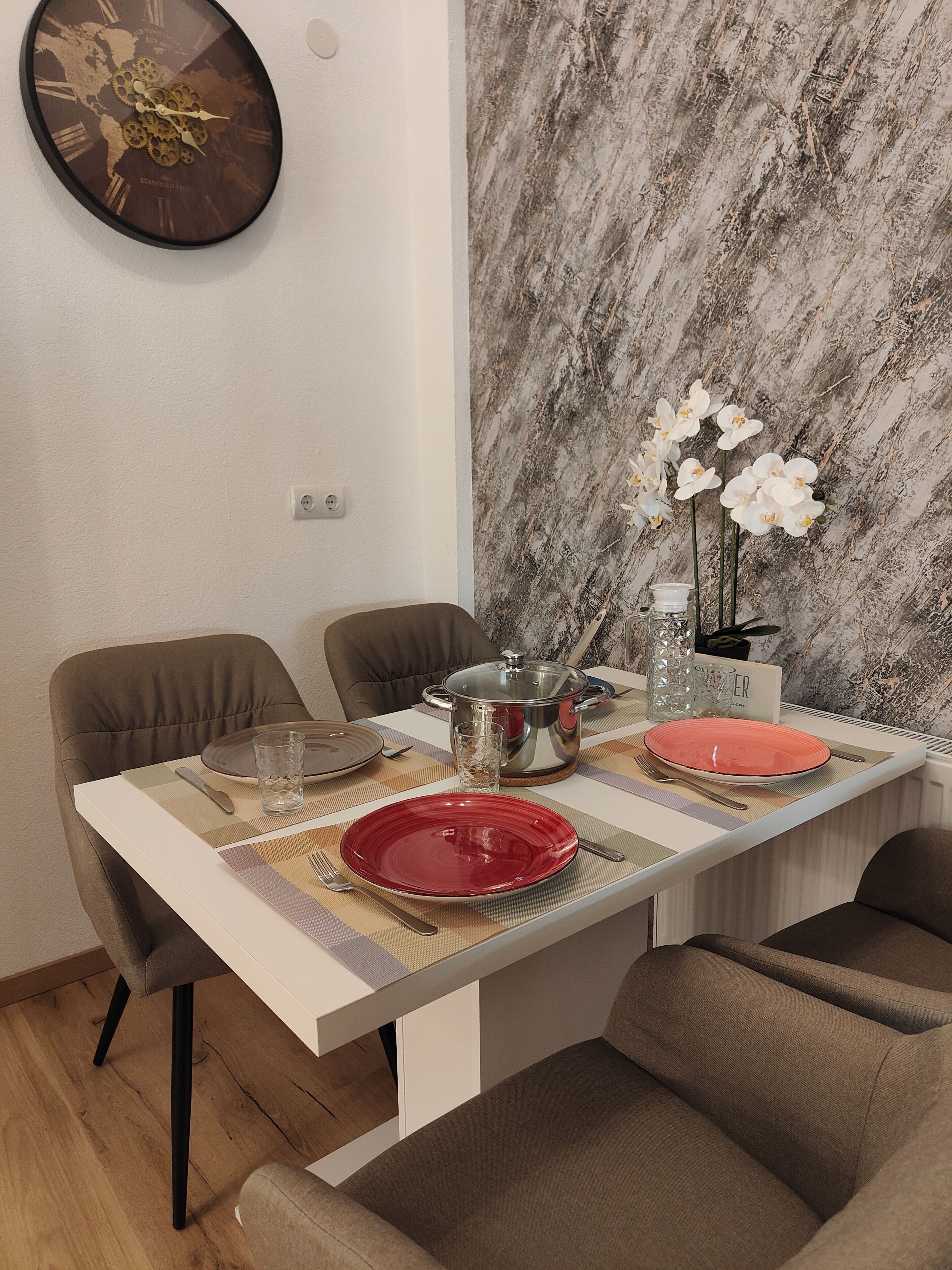 A dining table set with plates, cutlery, and a decorative vase with flowers.
