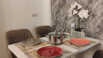 A dining table set with plates, cutlery, and a decorative vase with flowers.