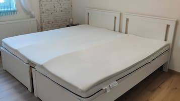 A white bed with a mattress tag, a white headboard, and a wooden floor.