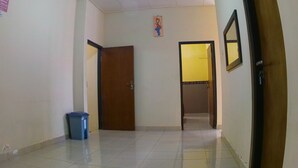 A hallway with a blue trash bin, a wooden door, and a yellow door leading to another room.