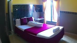 A hotel room with a bed, a nightstand, and a window with curtains.