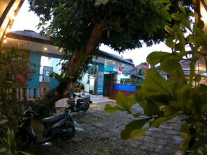 A building with a blue facade, a tree in the foreground, and two parked scooters.