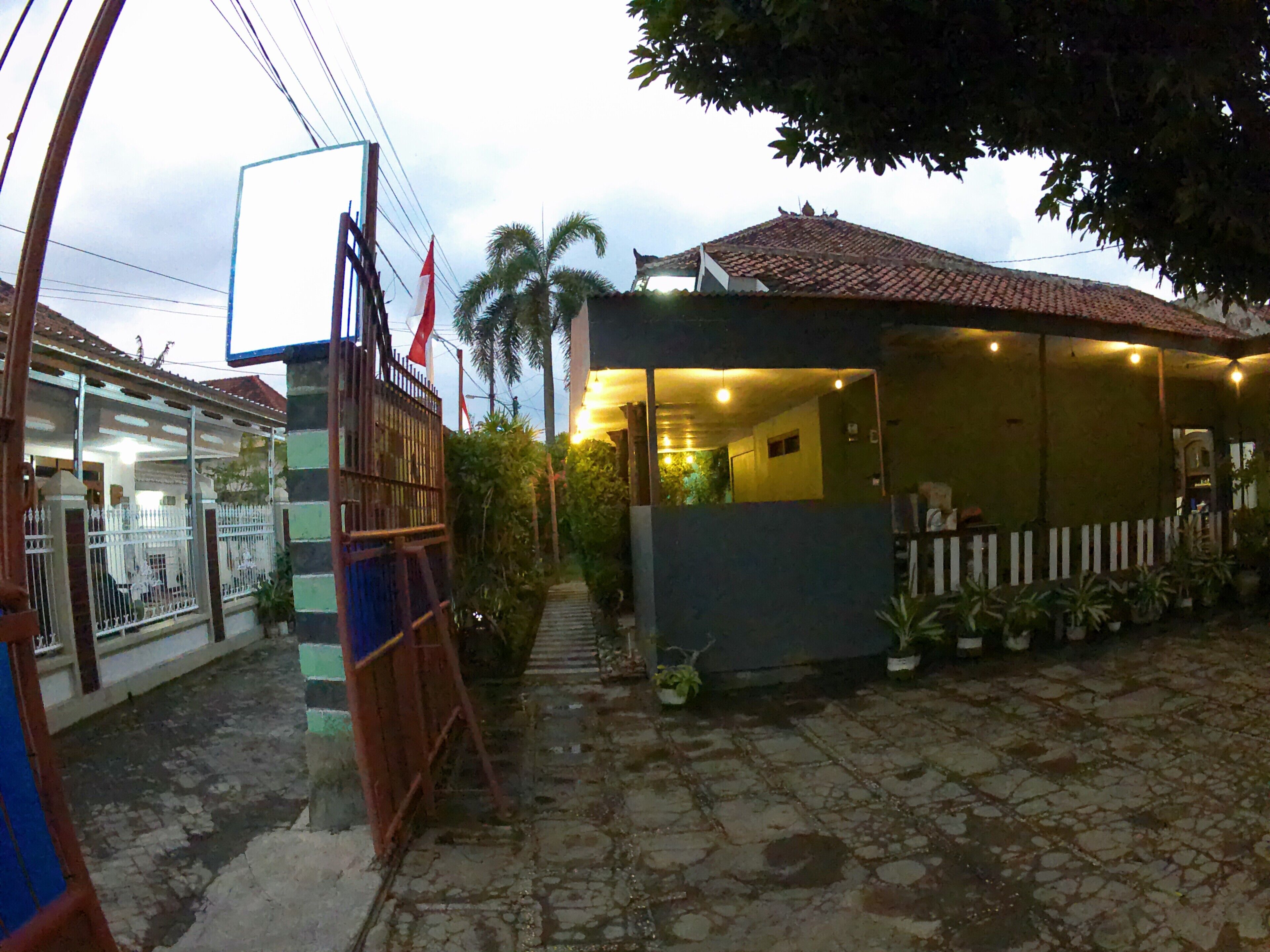 A courtyard with a tiled floor, a small covered area with lights, and a white fence.