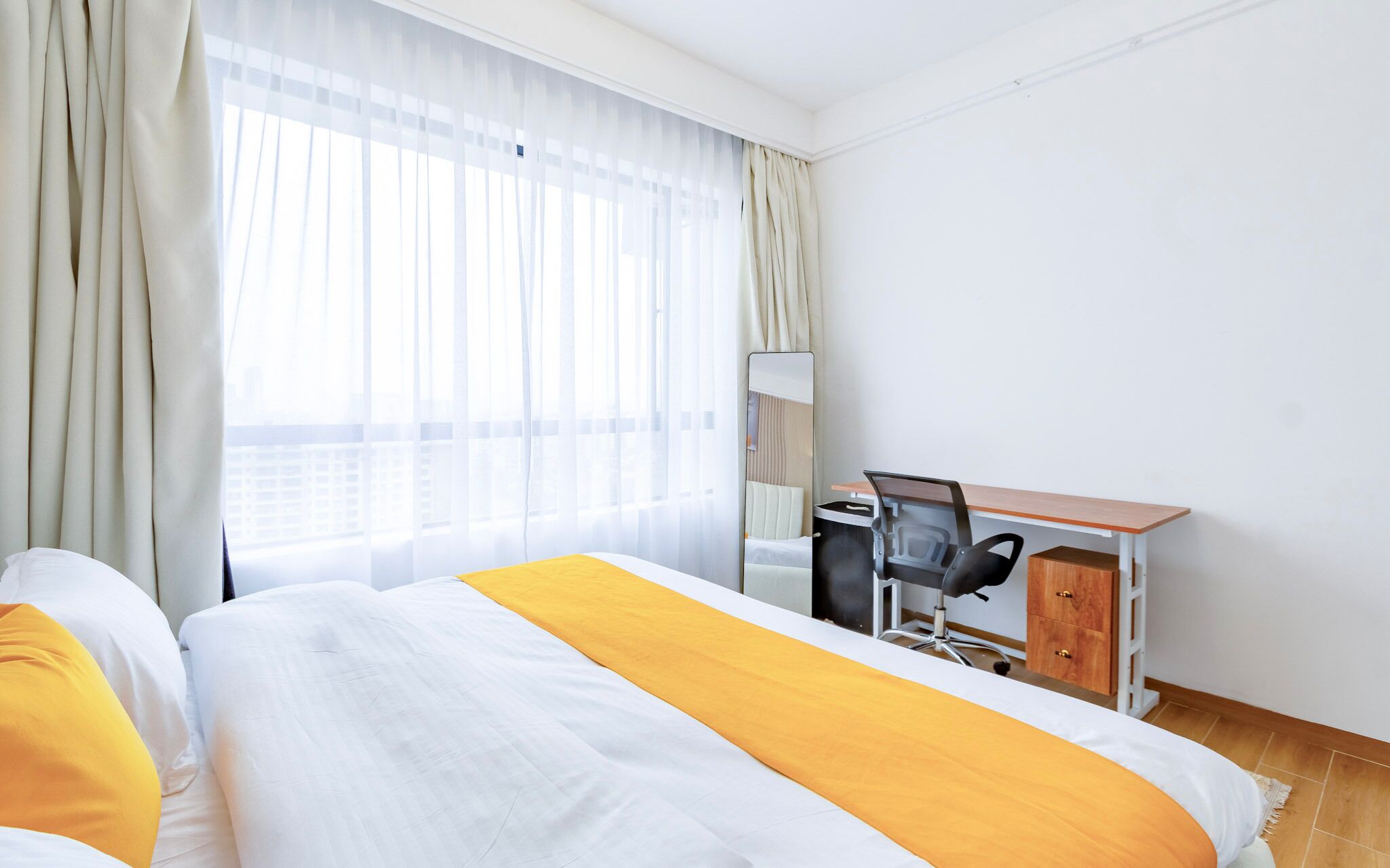 Une chambre d’hôtel avec un lit, un bureau, une chaise et un miroir.