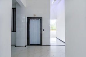 Un pasillo con una puerta marcada '1F' y un panel de control con botones.