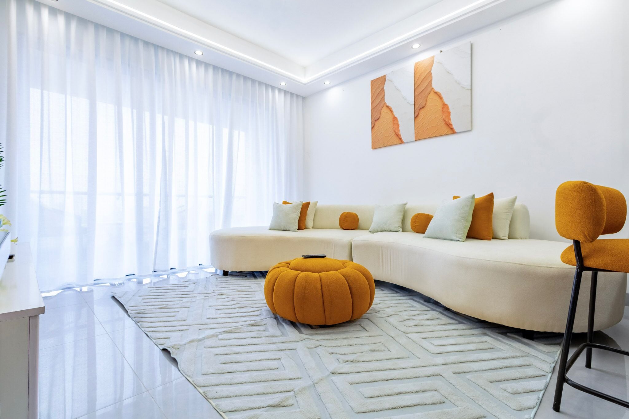 Ein modernes Wohnzimmer mit Ecksofa, Hocker und Barstuhl.