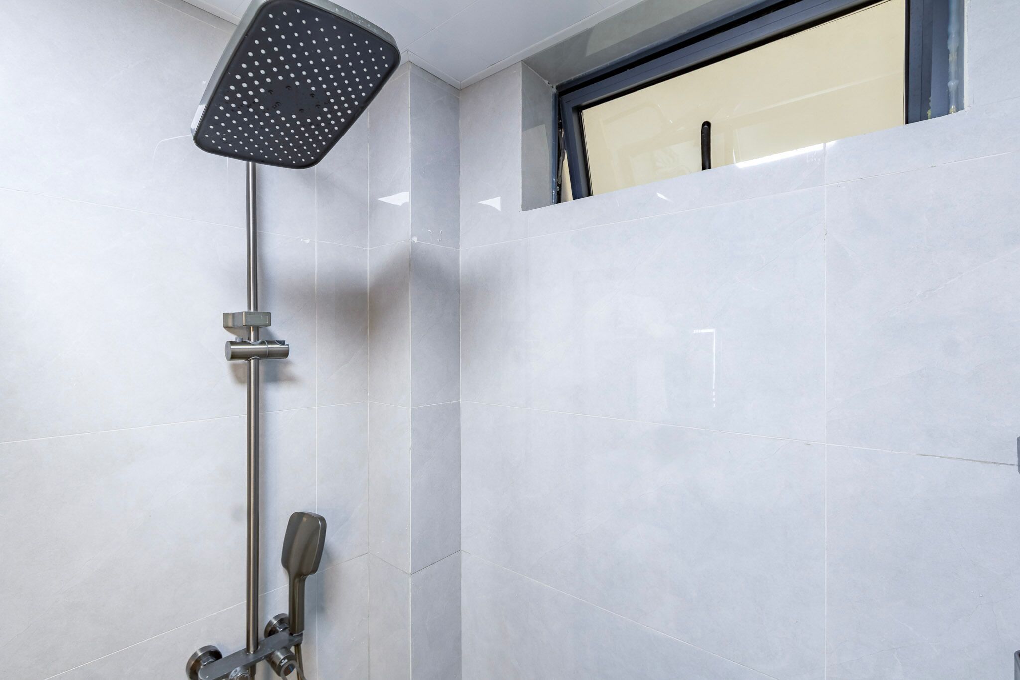 Une douche équipée d’un pommeau de douche à main et d’un robinet de contrôle fixé au mur.