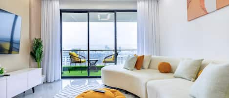 A modern living room with a sofa, ottoman, and a flat-screen TV.