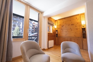 A room with two armchairs, a wooden wall, a window, and a view of buildings outside. - VAL D'ISERE, in the heart of the village, 2-room apartment with a terrace and parking (Val-d'Isère)