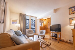 A living room with a sofa, two armchairs, a television on a wooden stand, and a window with curtains. - VAL D'ISERE, in the heart of the village, 2-room apartment with a terrace and parking (Val-d'Isère)