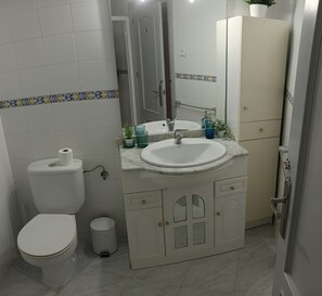 A bathroom with a toilet, sink, and mirror. - Beautiful two-bedroom, two-bathroom apartment with a pool in the center of Nerja (Nerja)