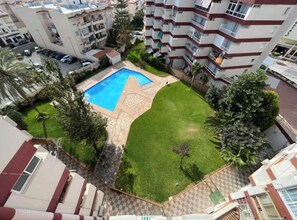 A residential building with a swimming pool surrounded by a well-maintained lawn and palm trees. - Beautiful two-bedroom, two-bathroom apartment with a pool in the center of Nerja (Nerja)