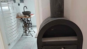 Et moderne køkken med en indbygget brændeovn, en hvid radiator og et lille bord med køkkenudstyr.