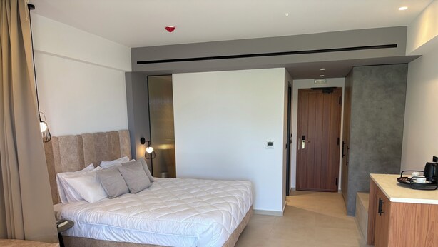 A modern hotel room with a large bed, bedside tables, a desk with a coffee maker, and a wardrobe. - Stella Elite Suites (Zakynthos)
