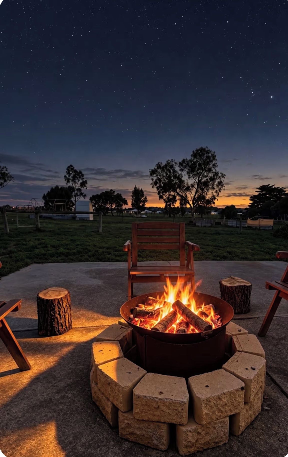 A fire pit with a chair in the foreground and a starry night sky in the background.