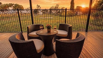 An outdoor seating area with wicker furniture and a view of a sunset.