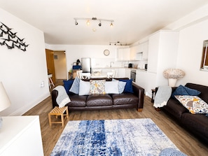 A modern living room with a brown leather sofa, a blue patterned rug, and a wooden side table.