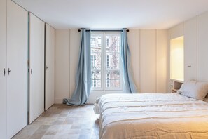 Een slaapkamer met een bed, een raam met gordijnen en een kledingkast.