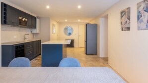 A modern kitchen with a central island, a dining area with a table, and a living space with a sofa. - 2BDR 2 Bath Rare Saint Germain des Pres (Paris)