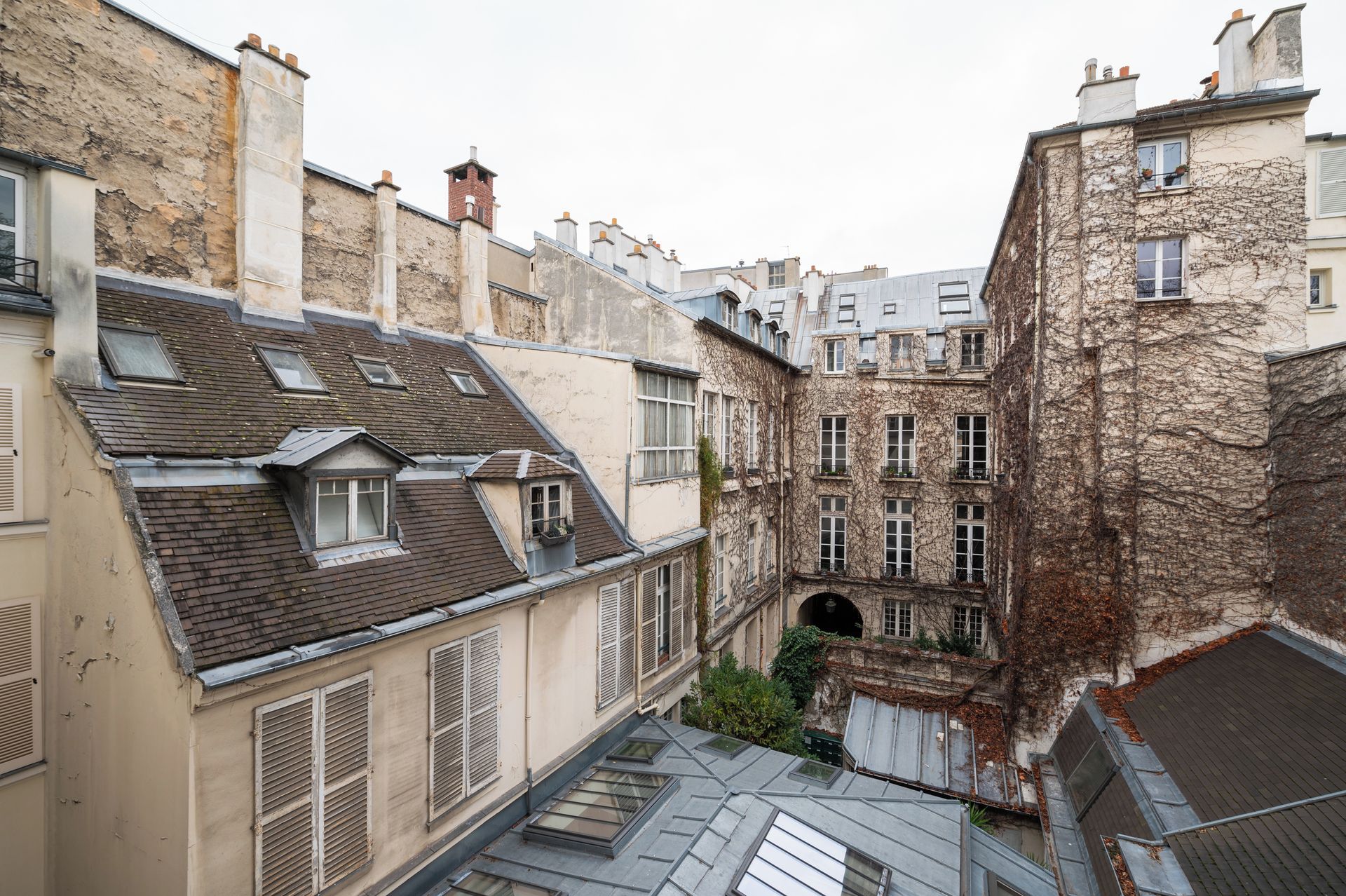 A narrow alleyway between buildings with traditional architecture, including stone facades and pitched roofs.