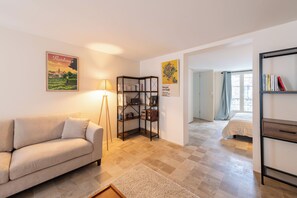 Een woonkamer met een bank, een vloerlamp, een boekenkast en een schilderij van Bordeaux.