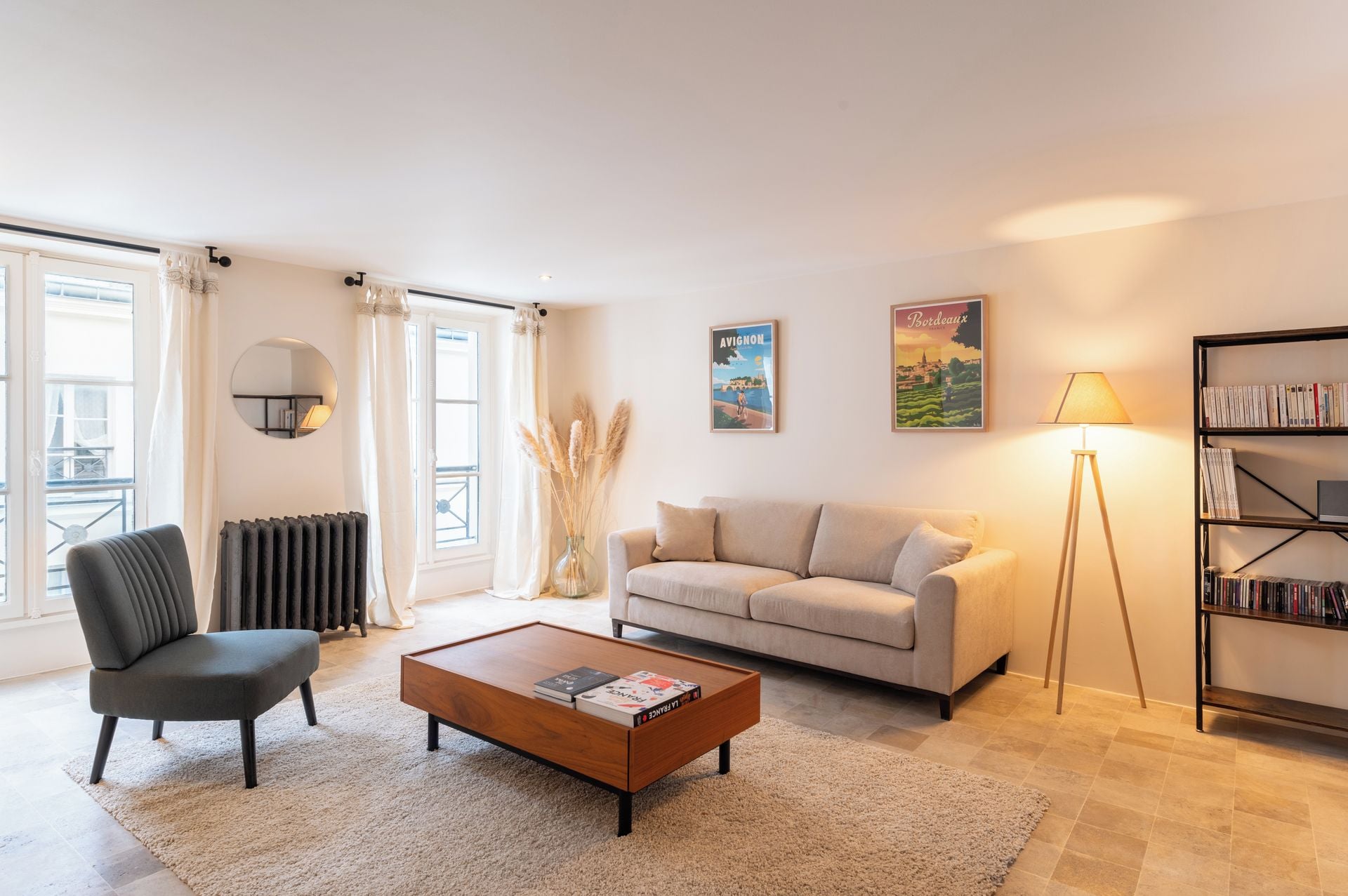 A living room with a sofa, a coffee table, a chair, a bookshelf, and a radiator.
