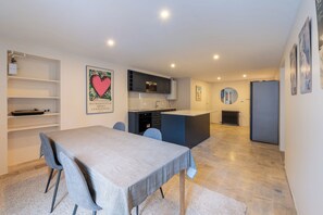 A modern kitchen with a central island, a dining area with a table and chairs, and a living space with a sofa. - 2BDR 2 Bath Rare Saint Germain des Pres (Paris)