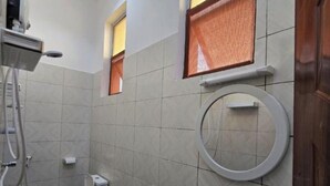 Et lille badeværelse med toilet, håndvask og brusebad.