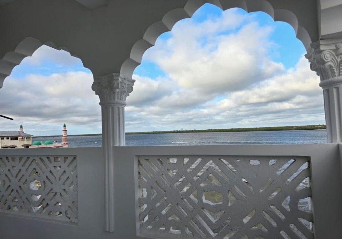 Vista a través de una celosía blanca decorativa con cielo despejado y una costa distante.