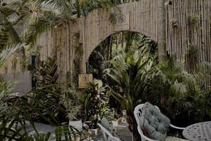 A private garden area with a bamboo fence, various tropical plants, and outdoor seating. - Spice Koh Phangan (Ko Pha-ngan)