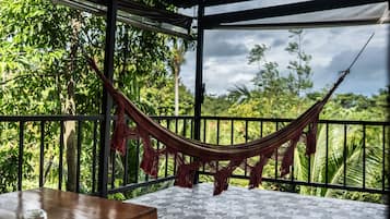 Una hamaca en un balcón con vistas a exuberante vegetación.