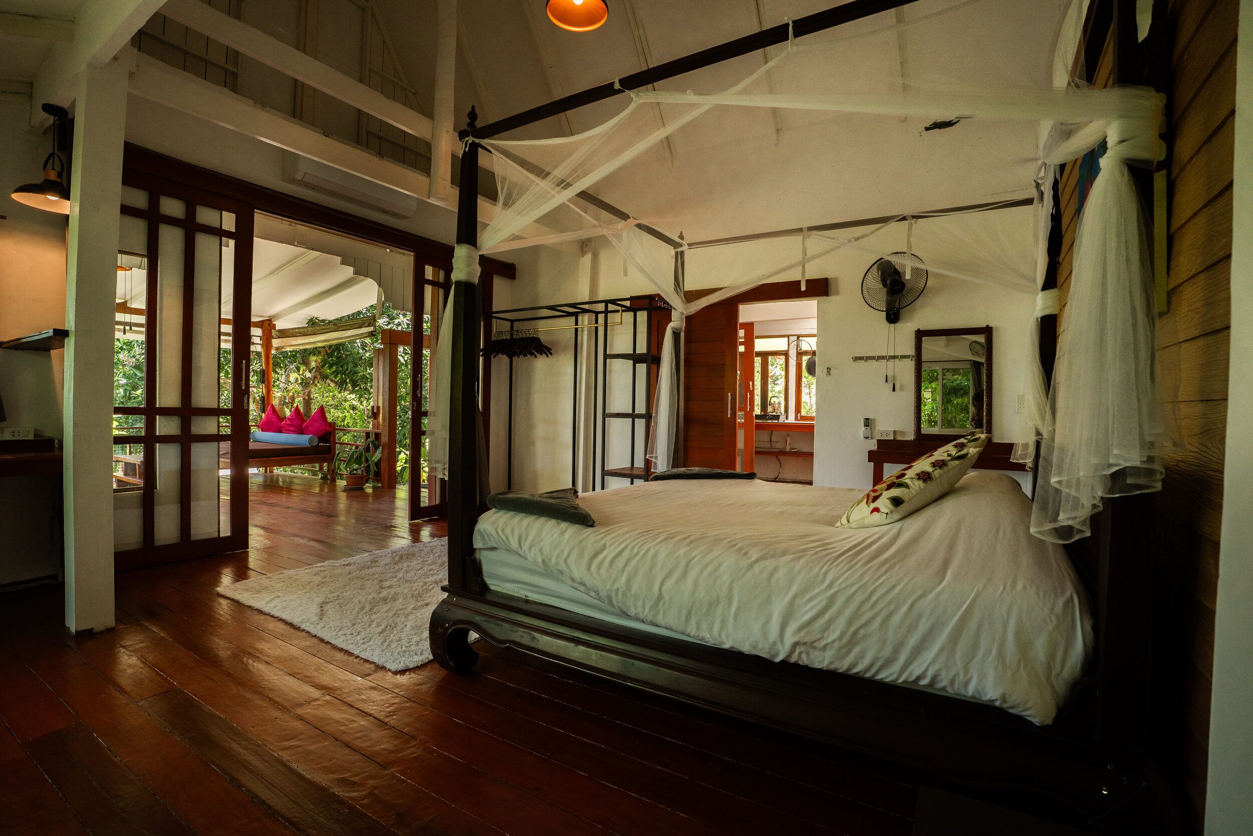 Ein geräumiges Schlafzimmer mit einem großen Bett, einem Deckenventilator und Blick ins Freie.