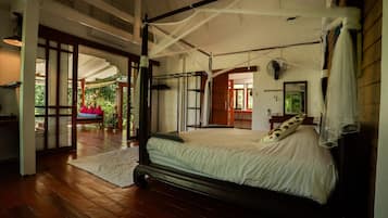 Ein geräumiges Schlafzimmer mit einem großen Bett, einem Deckenventilator und Blick ins Freie.