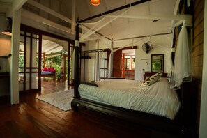Un dormitorio espacioso con una cama grande, ventilador de techo y vistas al exterior.