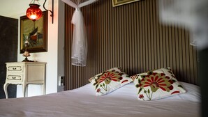 Et soveværelse med en seng, puder, et natbord, en lampe, et billede og et vindue med persienner.