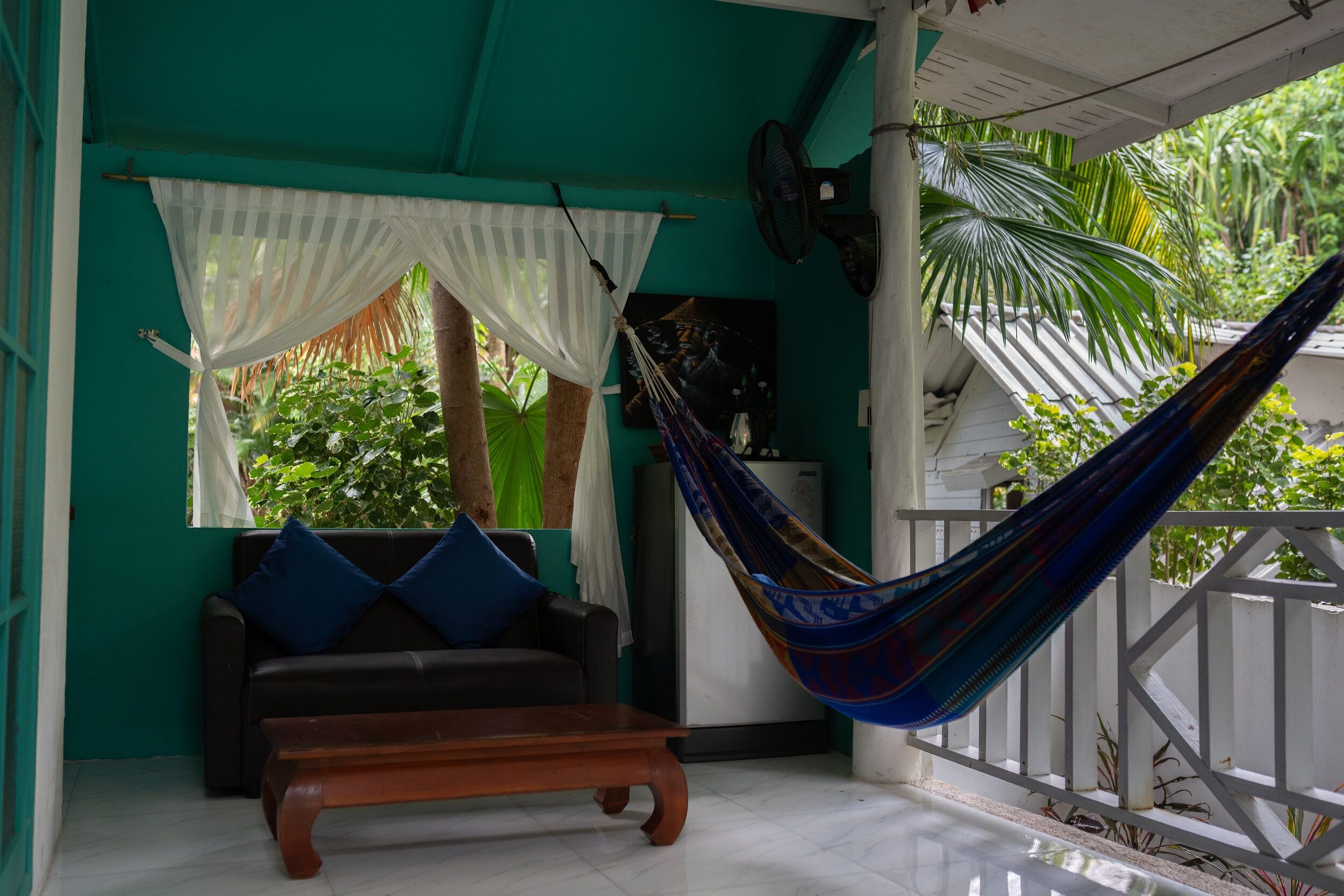 A room with a hammock, a sofa, and a bench.