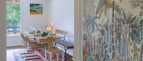 A dining area with a wooden table, chairs, and a colorful rug.